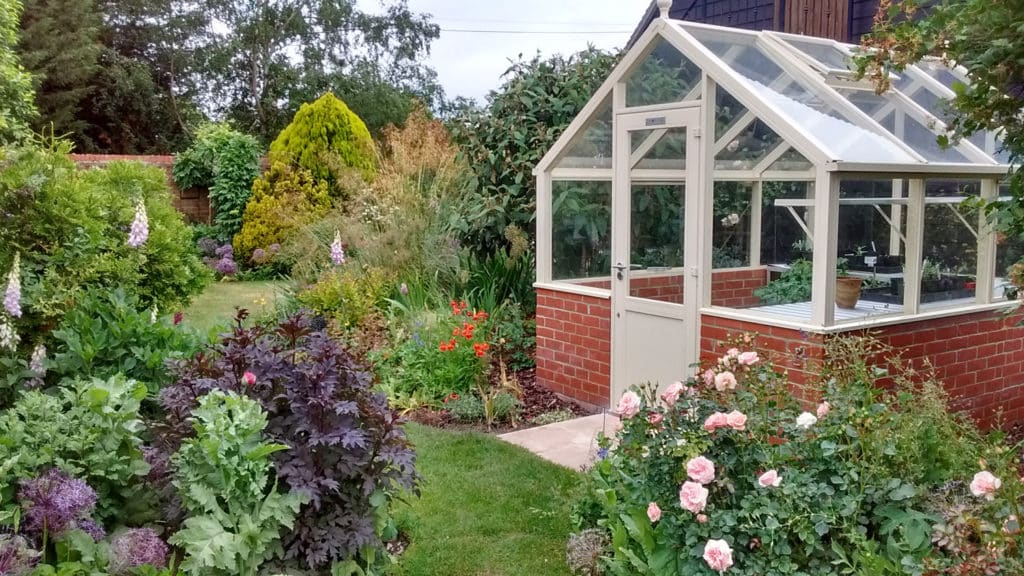 pretty greenhouse in landscaped garden