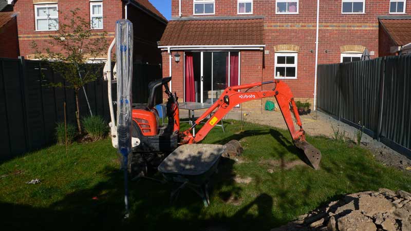 mini digger beginning groundworks in the back garden of a two bedroom estate house in Colchester