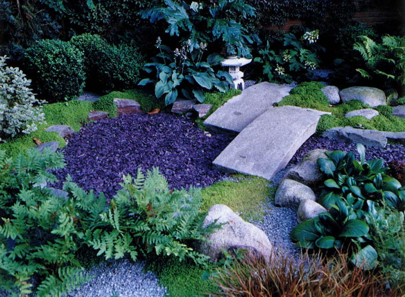 zen garden with dark coloured aggregate to represent water and lots of moss, ferns and boulders.