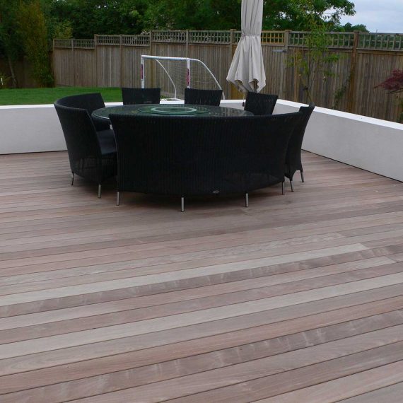 large area of garden decking with circular dining table and rattan chairs