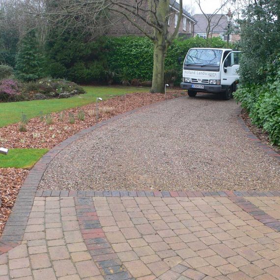 curving driveway with sandstone pavers in the foreground and gravel drive to the background