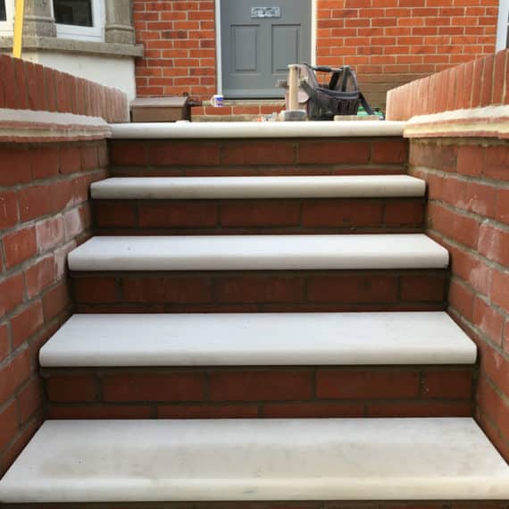 garden steps leading between two brick walls. brick risers and white stone treads