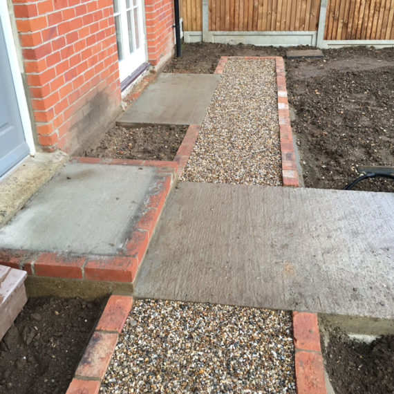 gravel path intersected by concrete base for a ceramic tiled path