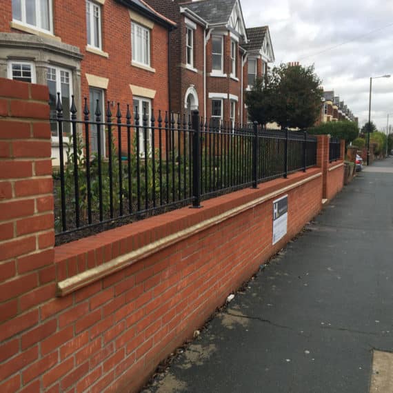 street view of newly built retaining wall topped by elegant iron railings in the Edwardian style