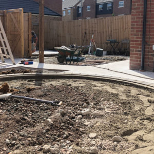 a garden under construction with a landscaper creating a patio area in the part of the garden with most privacy