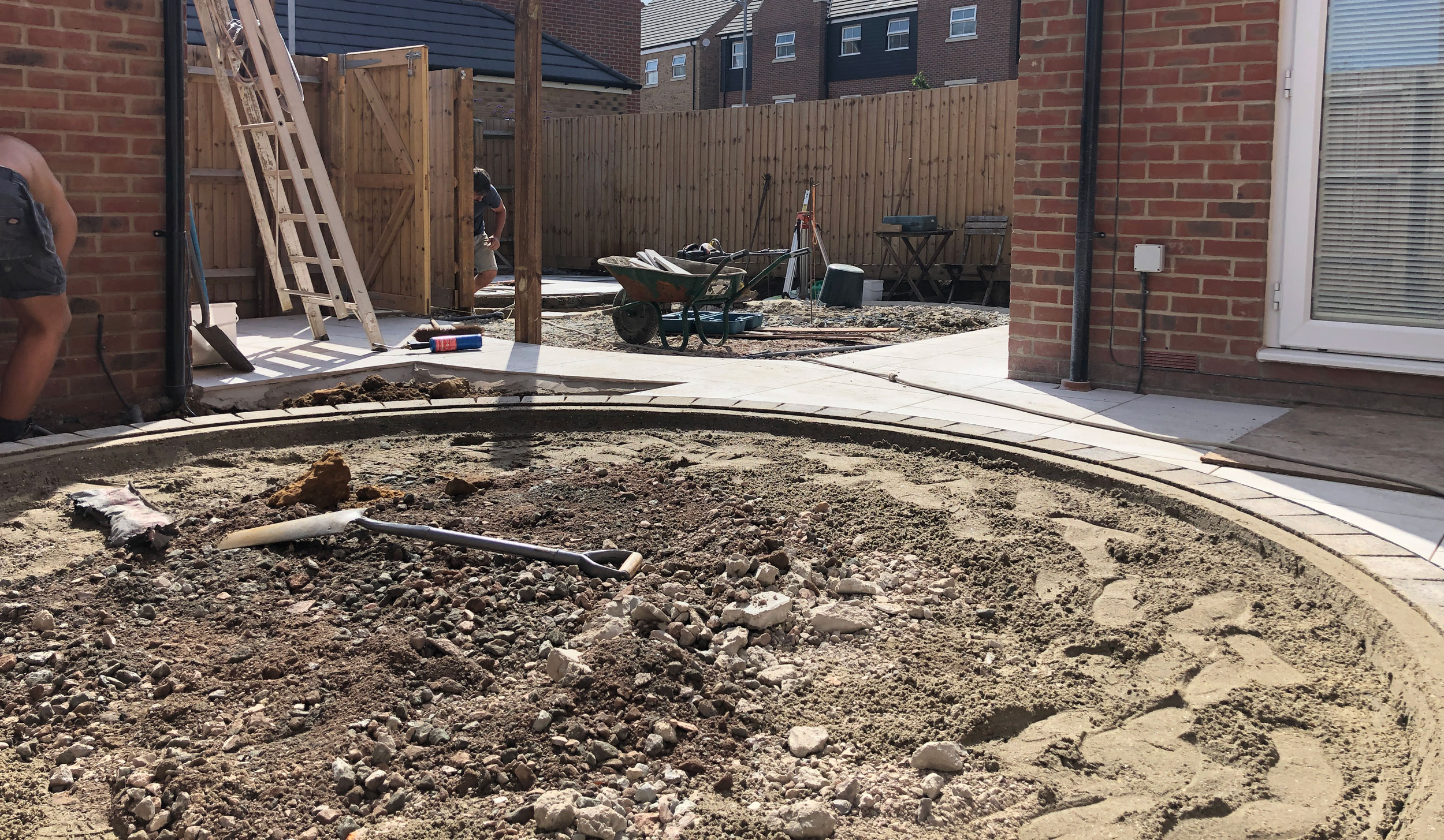a garden under construction with a landscaper creating a patio area in the part of the garden with most privacy