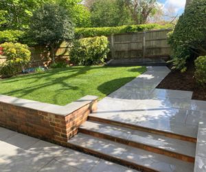 pretty garden with retaining wall in the foreground leading to lawns and planting