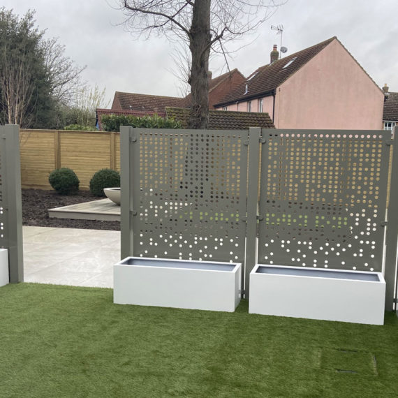articicial grass area with bespoke metal screening with rectangular white planters at the base