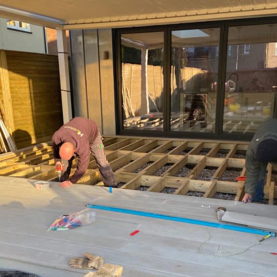 landscaper nailing composite decking boards to supporting structure