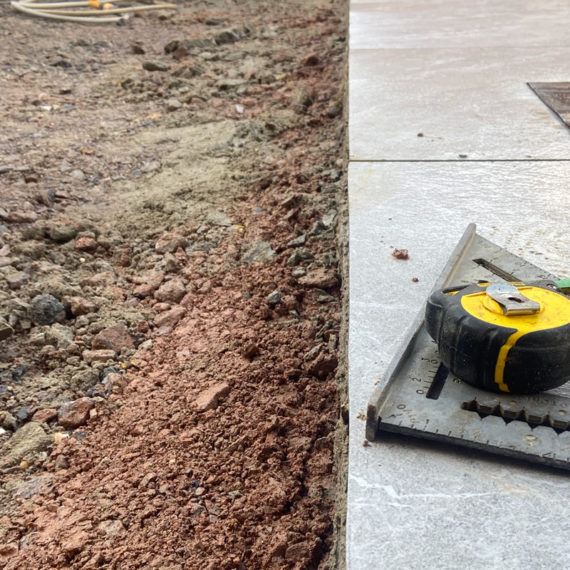 tape measure and set square sittting on porcelain slabs with patio base visible to the left of the picture
