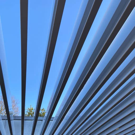 blue sky visible through the roof louvres of a contemporary pergola