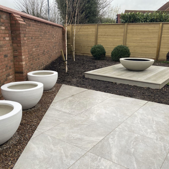 triangular patio with planters set between porcelain slabs and brick wall