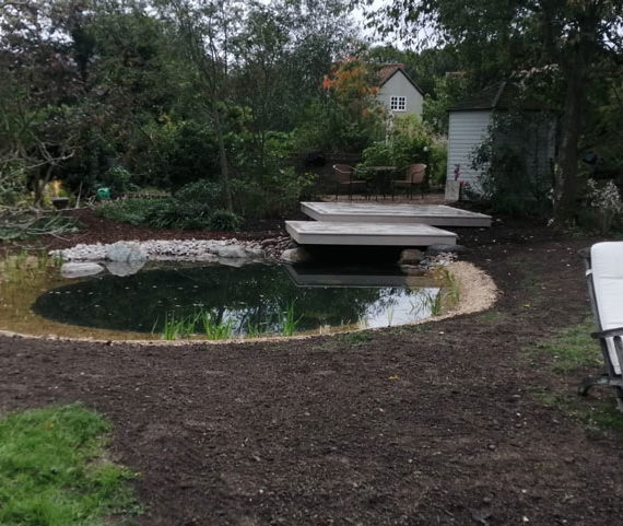 recently created informal garden pond with surrounding soil ready for seeding