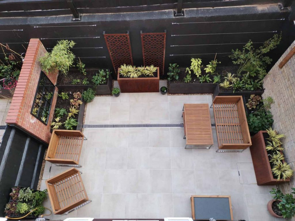 view from an upstairs window of a small courtyard garden elegantly landscaped with planters and paving