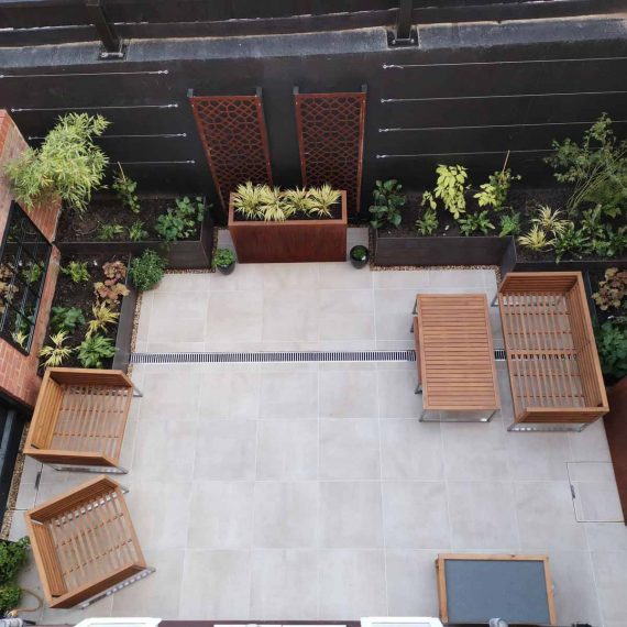 view from an upstairs window of a small courtyard garden elegantly landscaped with planters and paving