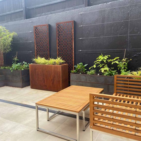 tasteful modern courtyard garden with black painted walls and natural wood furniture