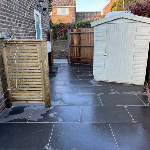 black granite paved area with garden shed and timber bin store