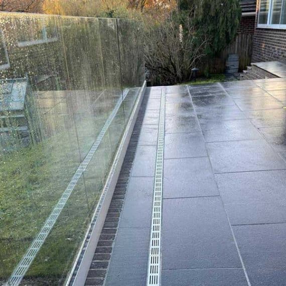 black granite patio with steel threshold drains and contemporary glass balustrade