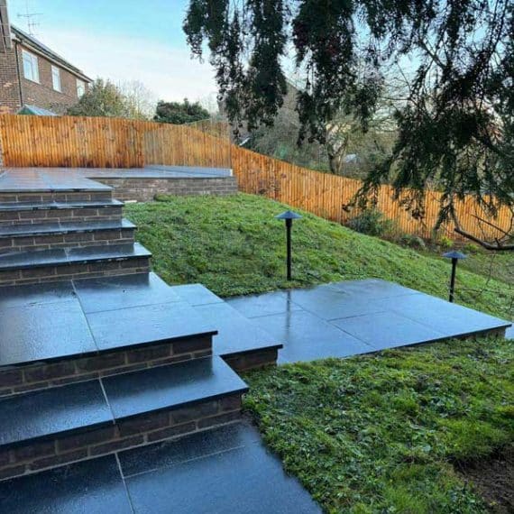 garden stairs set into a black granite path at the top of a sloping garden